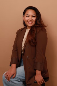 asian woman wearing a brown blazer and jeans