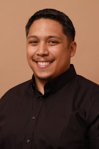 a man in a black shirt smiling for the camera